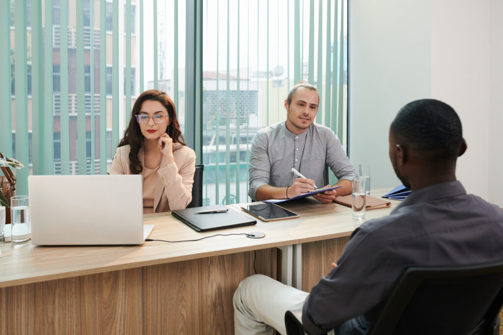 A young male job applicant being interviewed by two hiring managers.