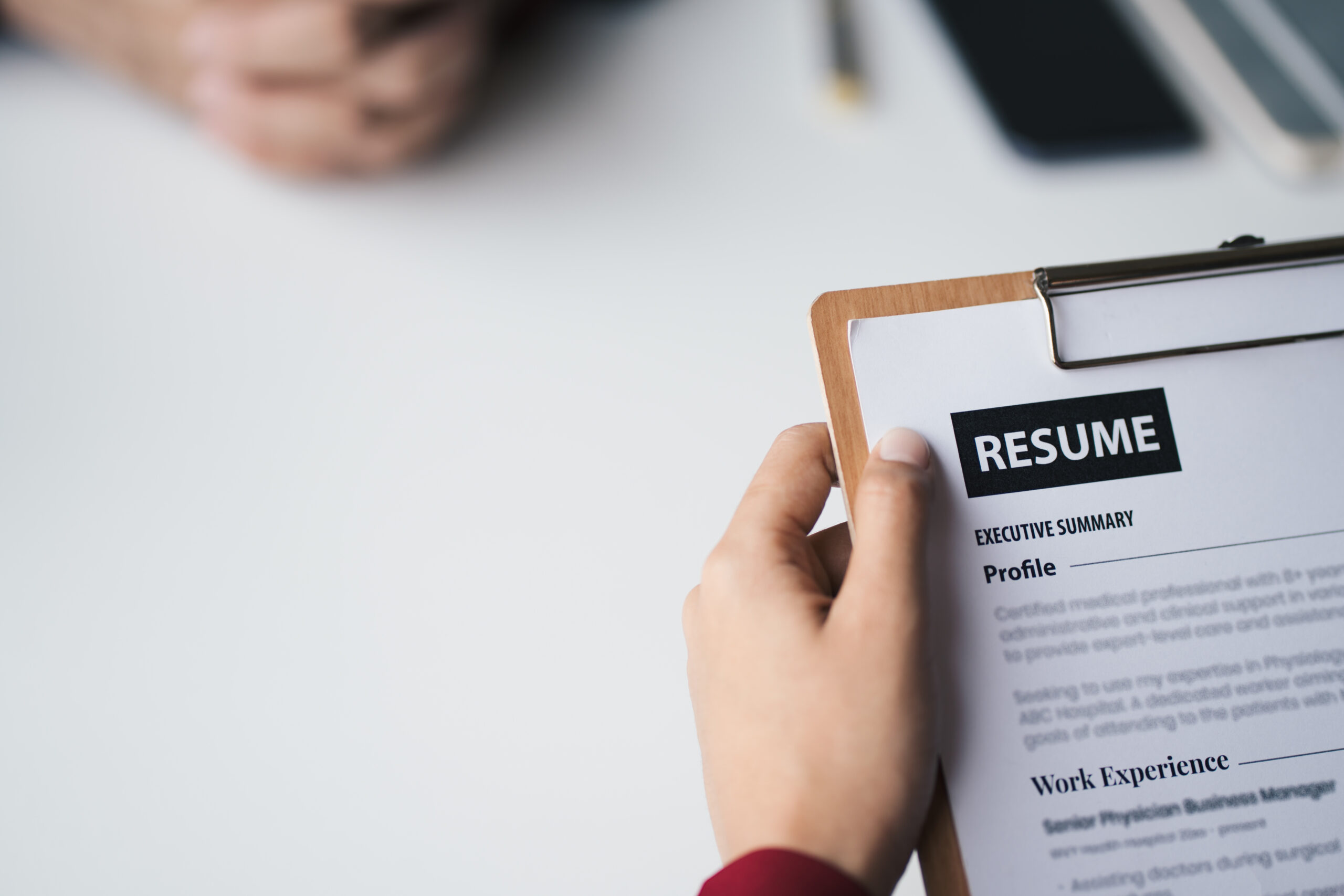 A close-up view of an employer reviewing a resume while the candidate sits across the table.